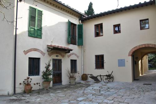 a white house with green shutters and a courtyard at CASA AL MIGLIO in Pratolino