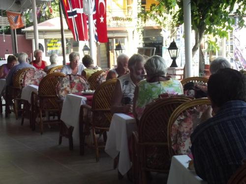 a group of people sitting at tables in a restaurant at Derya Motel in Side