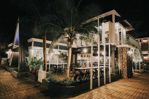 a restaurant with a table and palm trees at night at Royale Chenang Resort in Pantai Cenang