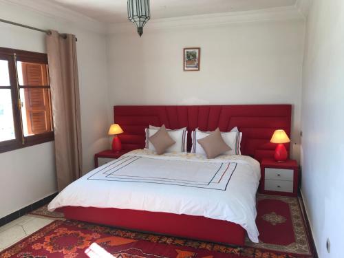 a bedroom with a large bed with a red headboard at Riad Villa Midelt in Midelt