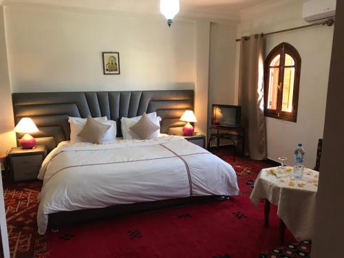 a bedroom with a large white bed with a red carpet at Riad Villa Midelt in Midelt