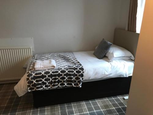 um quarto com uma cama com um cobertor e almofadas em Whisky Capital Inn em Dufftown