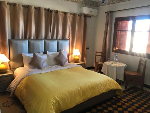 a bedroom with a large bed with a yellow blanket at Riad Villa Midelt in Midelt