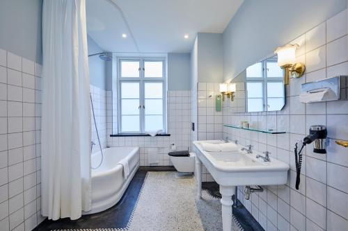 a bathroom with a sink and a tub and a toilet at Hotel Randers in Randers