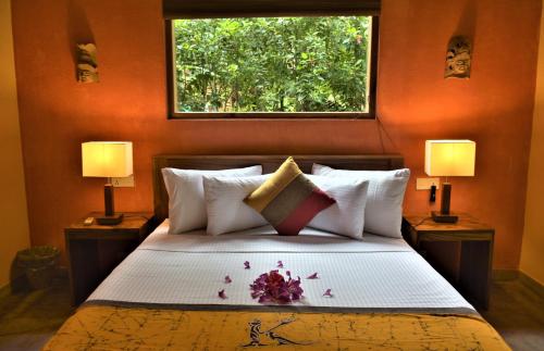 1 dormitorio con 1 cama con 2 lámparas y una ventana en Kuwera Eco Lodge en Sigiriya
