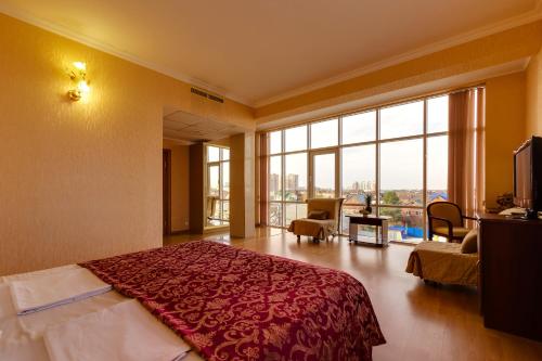 クラスノダールにあるVizit Hotelのベッドと大きな窓が備わるホテルルームです。
