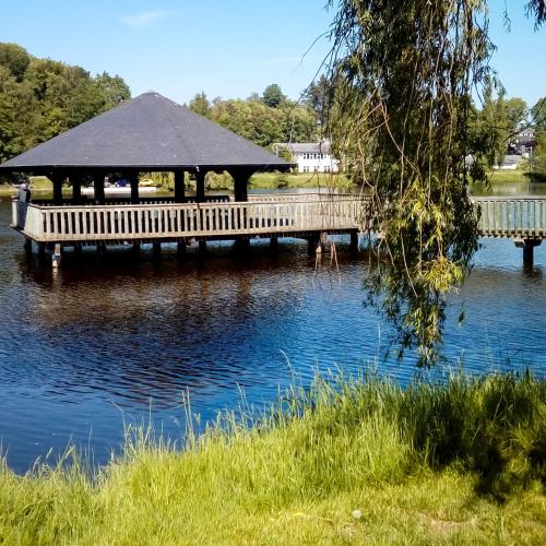 a wooden bridge over a lake with a gazebo at Una finestra sul lago in Vielsalm