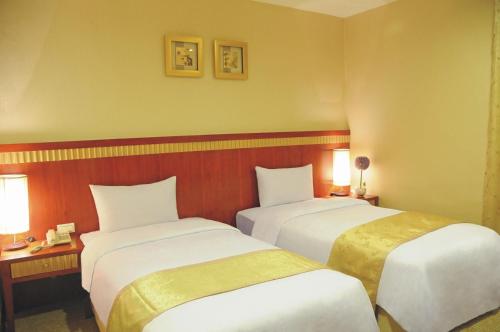 a hotel room with two beds and two lamps at Eastern Beauty Hotel in Taipei