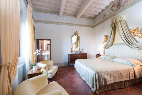 Un dormitorio con una cama y dos sillas y un espejo. en Villa di Cabbiavoli, en Castelfiorentino