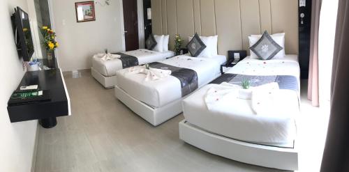 four beds in a room with white furniture at Muine Sports Hotel in Mui Ne