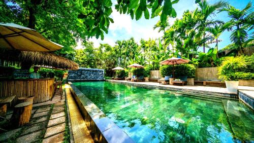 a swimming pool with chairs and umbrellas in a resort at La Residence Blanc D'Angkor in Siem Reap