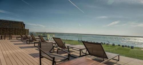 a row of chairs sitting on a deck near the ocean at MeerBlickD21 in Norderney