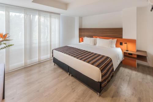 a bedroom with a large bed and large windows at Foresta Hotel in Medellín