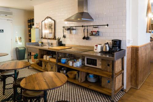 a kitchen with two tables and a counter with a microwave at Pars Teatro Hostel in Barcelona