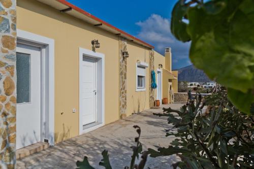 a row of yellow buildings with white doors at Montemar Studios & Apartments in Arkasa