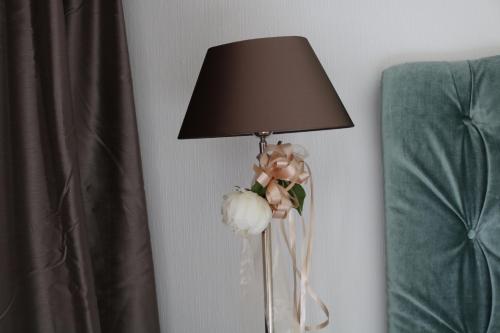 een lamp met bloemen in een vaas naast een bed bij Happy Homes in Haiger in Haiger