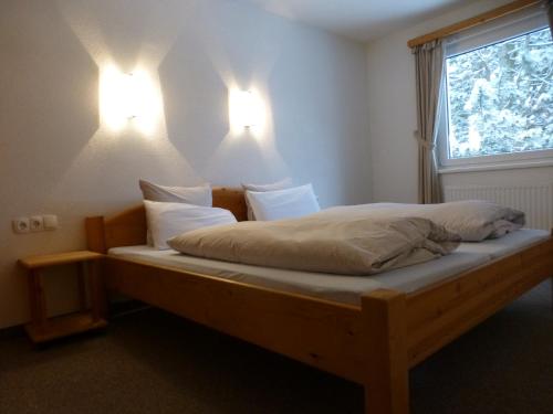 a bed in a room with two lights on the wall at Apart Auszeit in Arzl im Pitztal
