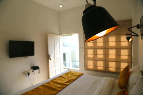a bedroom with a bed with a lamp and a window at Stay Banaras - A Boutique Hotel in Varanasi
