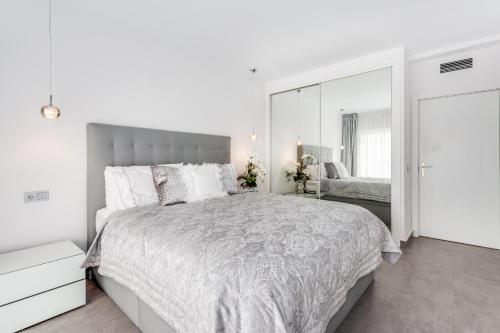 - une chambre blanche avec un grand lit et un miroir dans l'établissement by RIVA - Designer 1 Bedroom Apartment in the Centre of Marbella, à Marbella