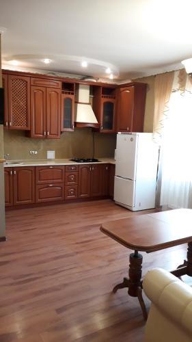 uma cozinha com armários de madeira, uma mesa e um frigorífico em Truskavets Elit Apartment em Truskavets