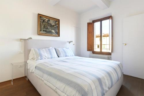 a white bedroom with a large bed with a window at Borgo Tegolaio Terrace in Florence
