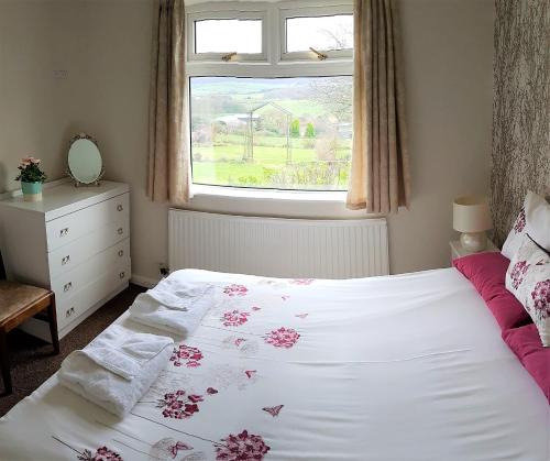 a bedroom with a white bed with a window at Woodpeckers Cottage in Scarborough