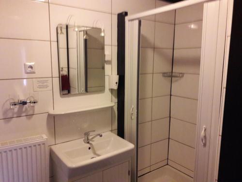 biała łazienka z umywalką i prysznicem w obiekcie Pension Hubertus w mieście Oberraden