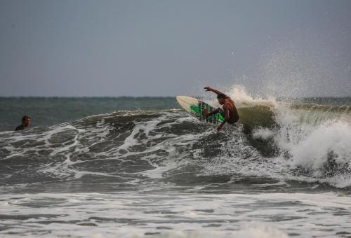 Ein Mann reitet eine Welle auf einem Surfbrett im Ozean in der Unterkunft Tapas & Surf in Petacaltepe