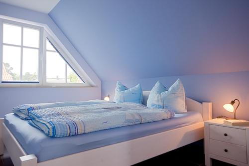 ein blaues Schlafzimmer mit einem Bett und einem Fenster in der Unterkunft Die Kleine Ferienwohnung in Prerow