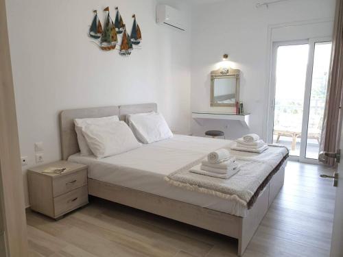 een witte slaapkamer met een groot bed en een spiegel bij Sea Breeze Villa in Charaki