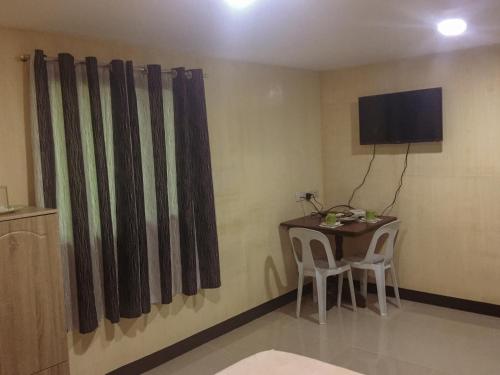 a room with a table and chairs and a television at Pitaya Native Guest House in Panglao
