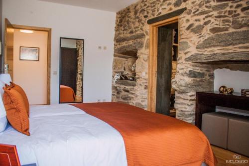 a bedroom with a bed and a stone wall at Terraços de Baco in Ribalonga
