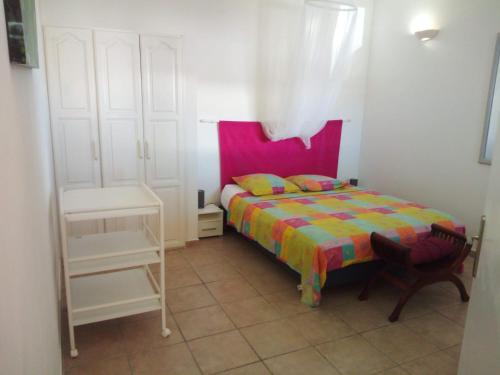 a small bedroom with a bed with a colorful blanket at Les petites vanilles in Les Trois-Îlets