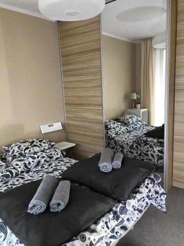 a bedroom with two beds with pillows and a mirror at Apartament koloru morza - Kobalt in Łeba