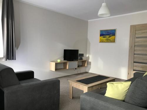 a living room with two couches and a tv at Apartament koloru morza - Kobalt in Łeba