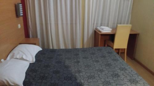 a hotel room with a bed and a desk and a desk at Guest House Estrela in Porto