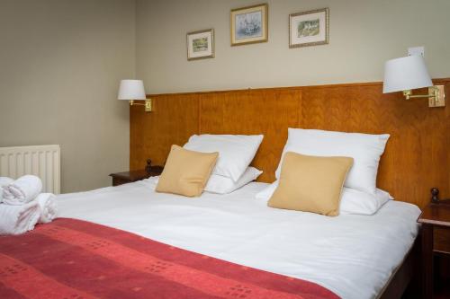 a bedroom with a large white bed with two pillows at Woolpack Inn in Eskdale