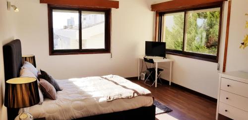 a bedroom with a bed and two windows at City Heart Rooms in Porto