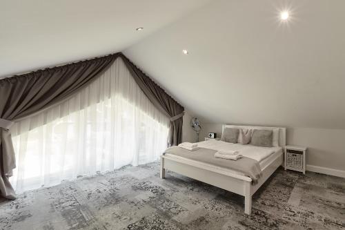 a bedroom with a bed and a large window at Górska Legenda Apartamenty & Domki in Szczyrk