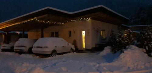 a house with snow covered cars parked in a driveway at Apart Lechtraum in Stanzach