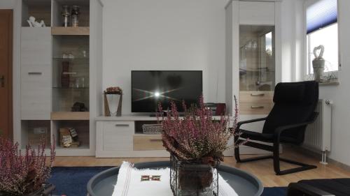 a living room with a tv and a chair and a table at Ferienwohnung Wössner in Oberndorf