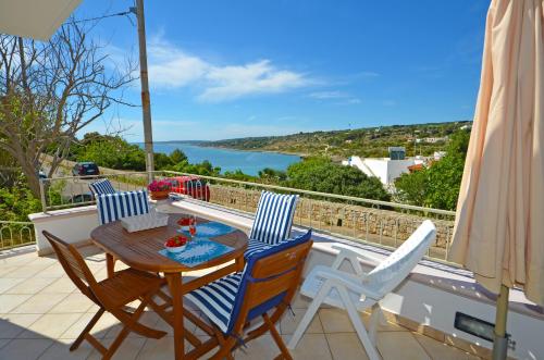 a table and chairs on a balcony with a view of the water at Casa Baia Tramonto in Patù