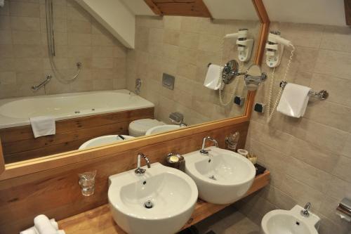 a bathroom with two sinks and a tub and a mirror at Bianca Resort & Spa in Kolašin