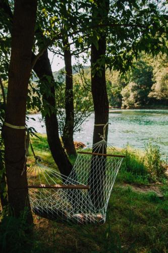 a hammock hanging between two trees next to a river at Anur House in Bihać