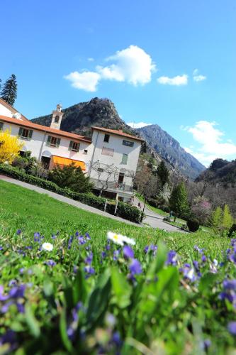 a building with a field of flowers in the foreground at Le Prieuré in Saint-Dalmas-de-Tende