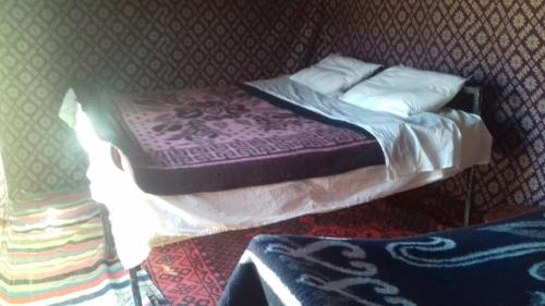 Una cama pequeña con sábanas y almohadas moradas. en Bivouac Dune Iriki, en Foum Zguid