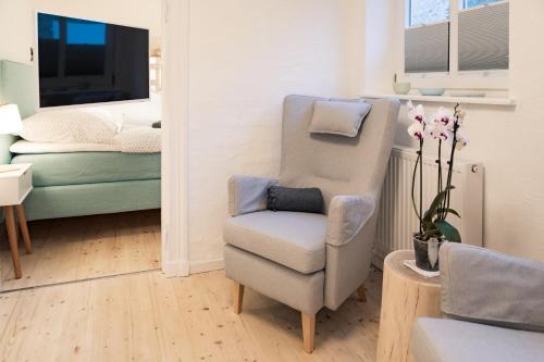 ein Wohnzimmer mit einem Stuhl und ein Schlafzimmer in der Unterkunft Smaaland in Flensburg