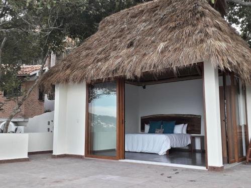 a room with a bed with a thatch roof at Ysuri Sayulita - Beachfront Hotel in Sayulita
