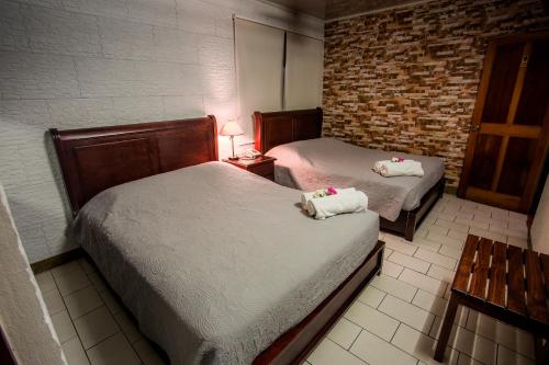 a bedroom with two beds and a brick wall at Boutique Hotel Casa Orquídeas in San José