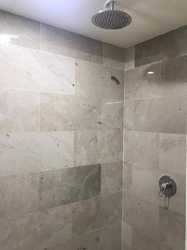a bathroom with a shower with a stone wall at Deluxe New Beachfront Penthouse in Akumal in Akumal
